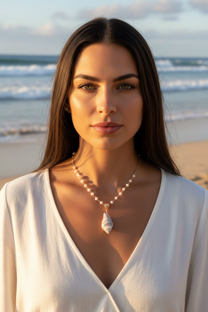 Close-up of a person wearing a necklace with a shell pendant, lying on a white surface.